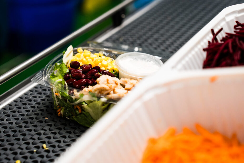 Fertig abgefüllter Salat-Cup mit Mais, Bohnen und Dressing auf dem Band