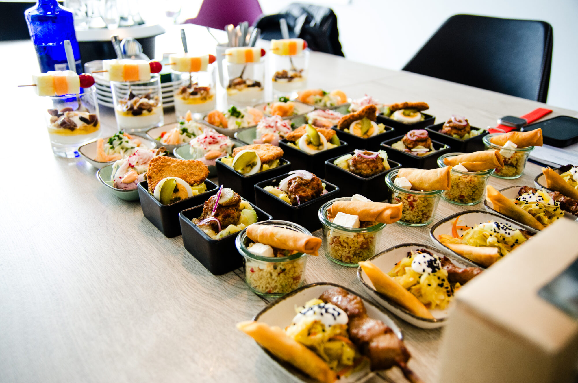 Fingerfood-Buffet auf einem langen Tisch, Schälchen und Gläser in Reihen