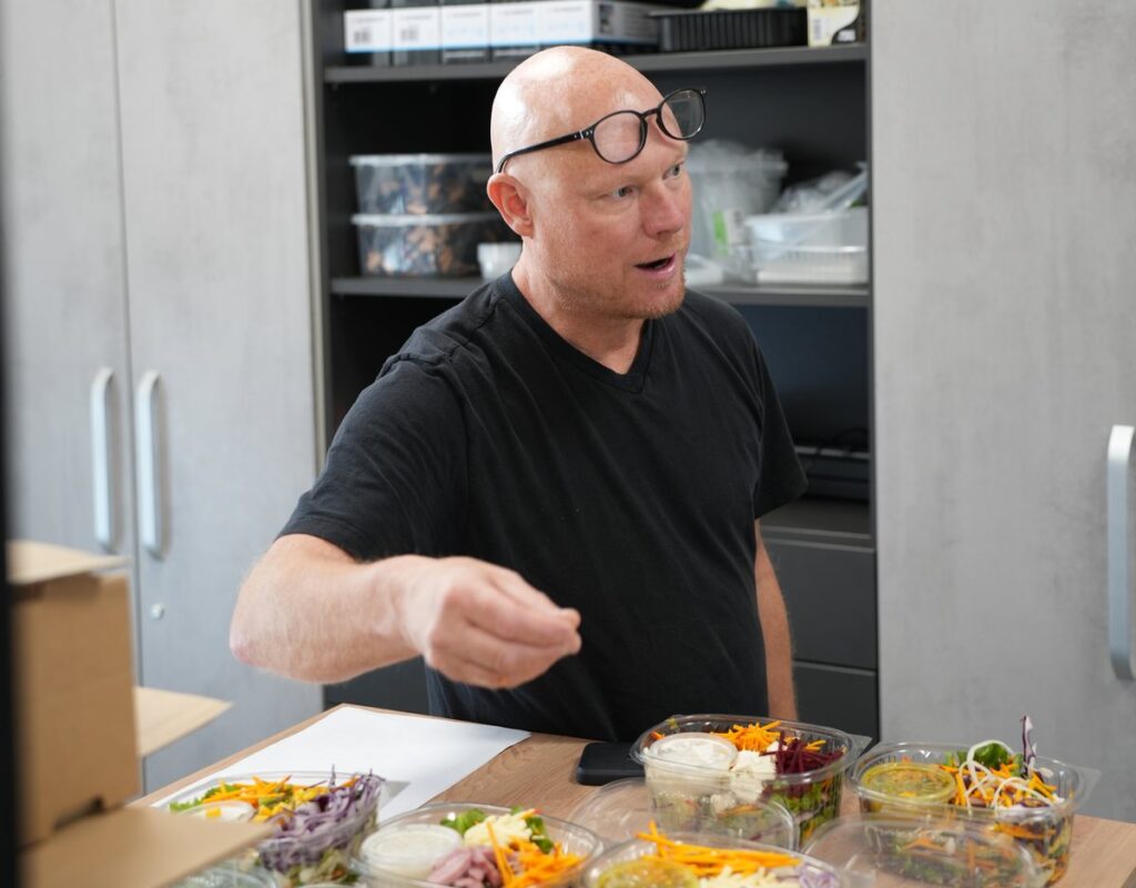 Ein Mitarbeiter bespricht fertige Salatschalen am Tisch