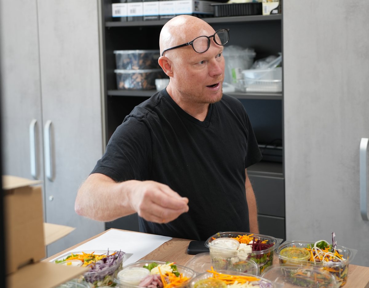 Ein Mitarbeiter bespricht fertige Salatschalen am Tisch